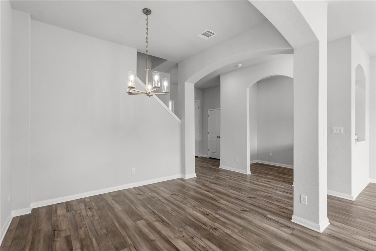 8513 Wellspring Loop Round Rock, TX 78665 - Photo 11 of 40 Unfurnished dining area with suspended lighting, arched walkways, and wood finished floors