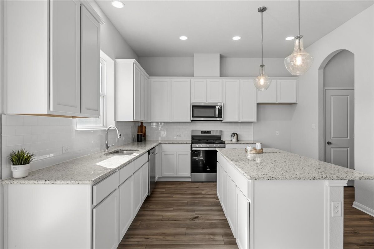 8513 Wellspring Loop Round Rock, TX 78665 - Photo 7 of 40 Kitchen with stainless steel appliances, a center island, arched walkways, and light stone countertops