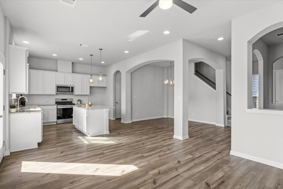 8513 Wellspring Loop Round Rock, TX 78665 - Photo 38 of 40 Kitchen with open floor plan, arched walkways, white cabinetry, stainless steel appliances, and a kitchen island