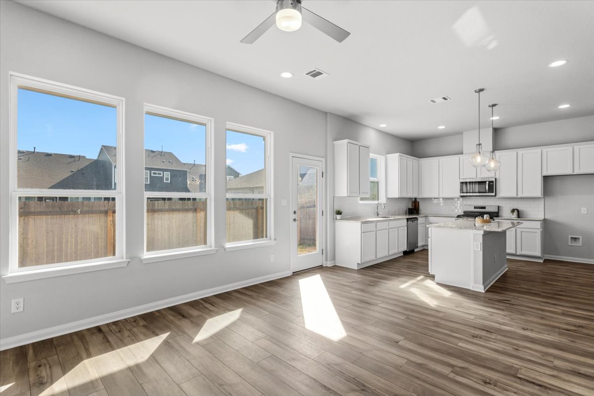8513 Wellspring Loop Round Rock, TX 78665 - Photo 39 of 40 Kitchen with a kitchen island, white cabinetry, ceiling fan, open floor plan, and decorative light fixtures
