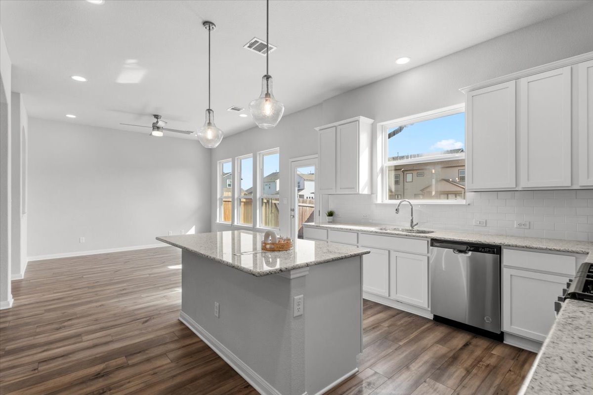 8513 Wellspring Loop Round Rock, TX 78665 - Photo 8 of 40 Kitchen featuring white cabinets, pendant lighting, stainless steel dishwasher, light stone counters, and backsplash