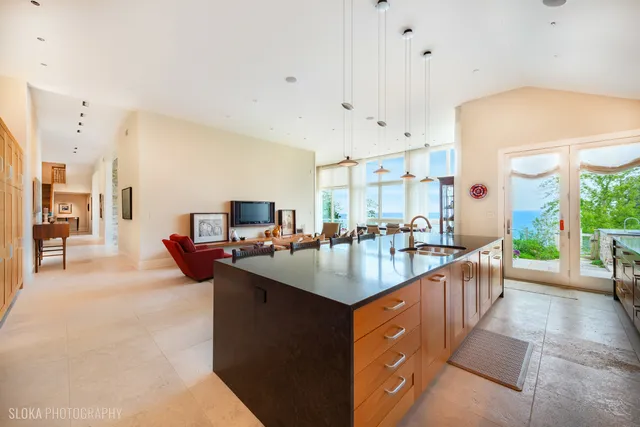 a living room with stainless steel appliances kitchen island granite countertop a sink and a refrigerator