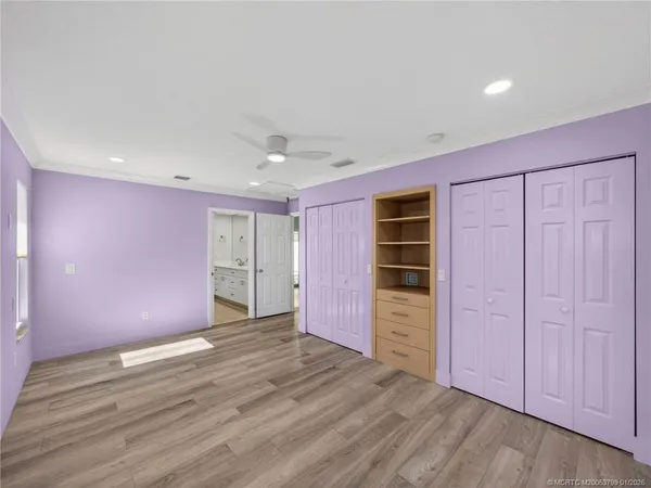 a view of an empty room with wooden floor and closet area