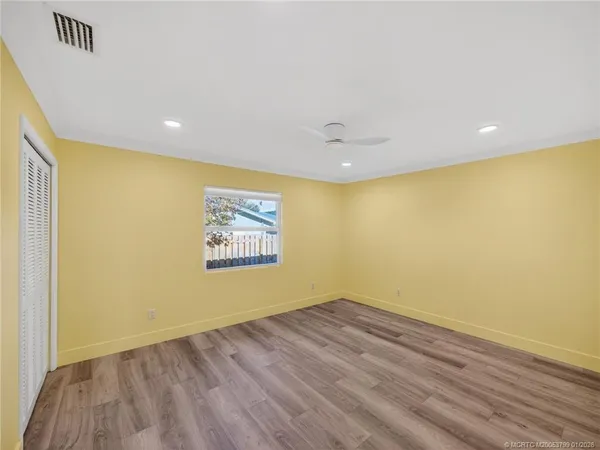 an empty room with wooden floor and windows