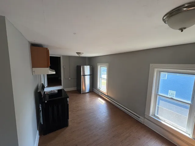 a view of a kitchen with refrigerator and wooden floor