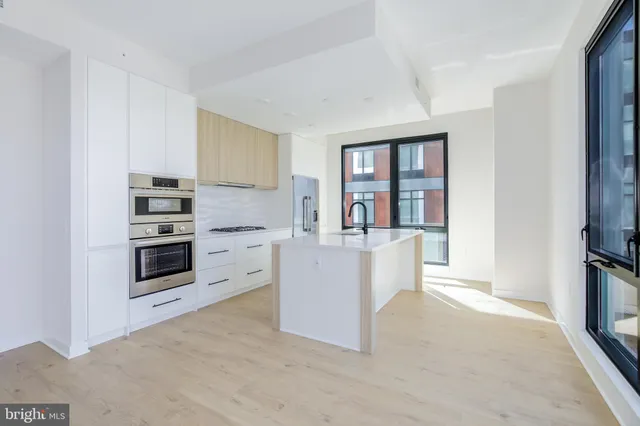 a kitchen with stainless steel appliances a stove top oven a sink a counter top space and cabinets