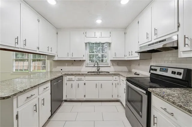 a kitchen with granite countertop cabinets stainless steel appliances a sink and dishwasher