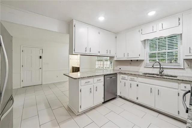 a kitchen with granite countertop white cabinets white appliances with a sink and a window