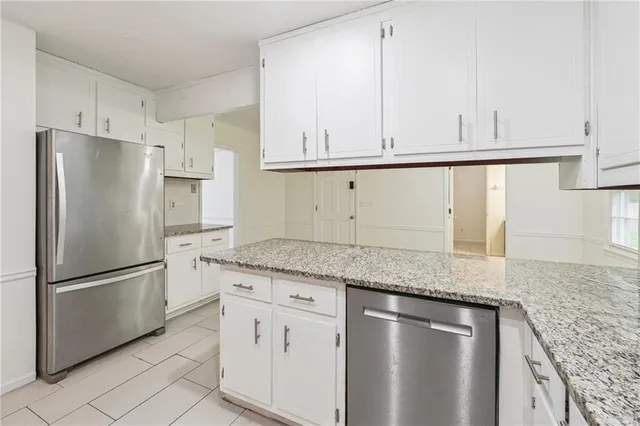 a kitchen with granite countertop stainless steel appliances white cabinets and a refrigerator