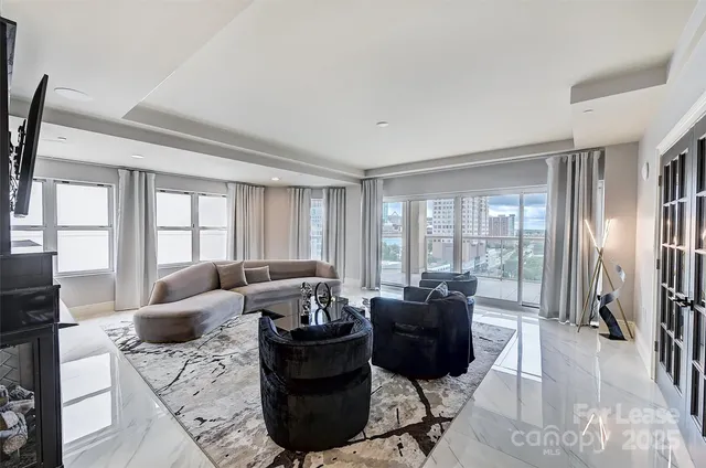 a living room with furniture fireplace and large windows