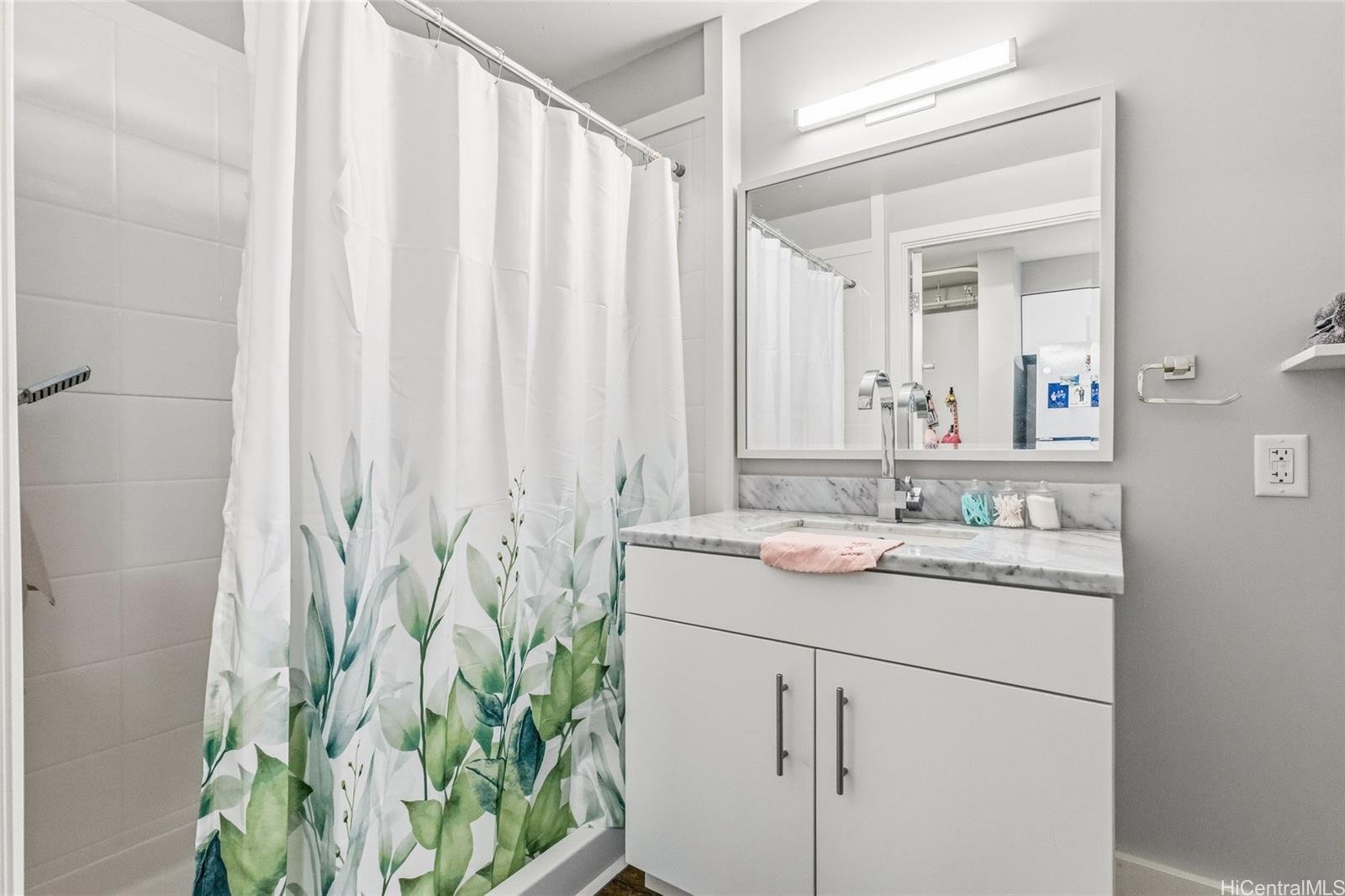 803 Waimanu Street, Unit 702 Honolulu, HI 96813 - Photo 4 of 19 a bathroom with a granite countertop sink a mirror and a shower curtain