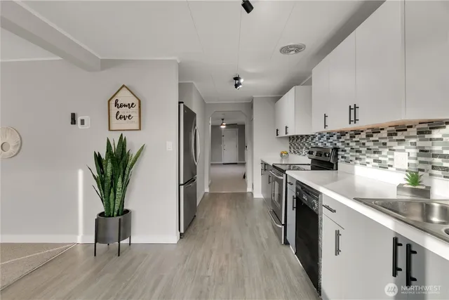 a kitchen with stainless steel appliances a sink a stove and a wooden floor