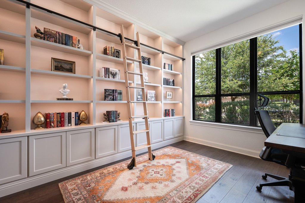 1221 Siena Sunset Road Leander, TX 78641 - Photo 7 of 39 Built-in wall shelving with recessed lighting and a rolling ladder, complemented by dark wood-finish flooring and a large picture window