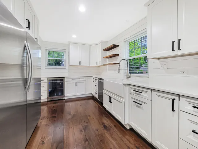 a kitchen with granite countertop a stove a sink dishwasher a refrigerator and white cabinets with wooden floor