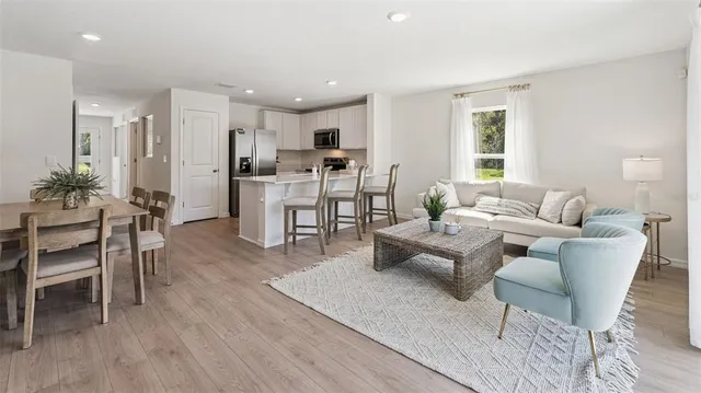 a living room with furniture kitchen view and a wooden floor
