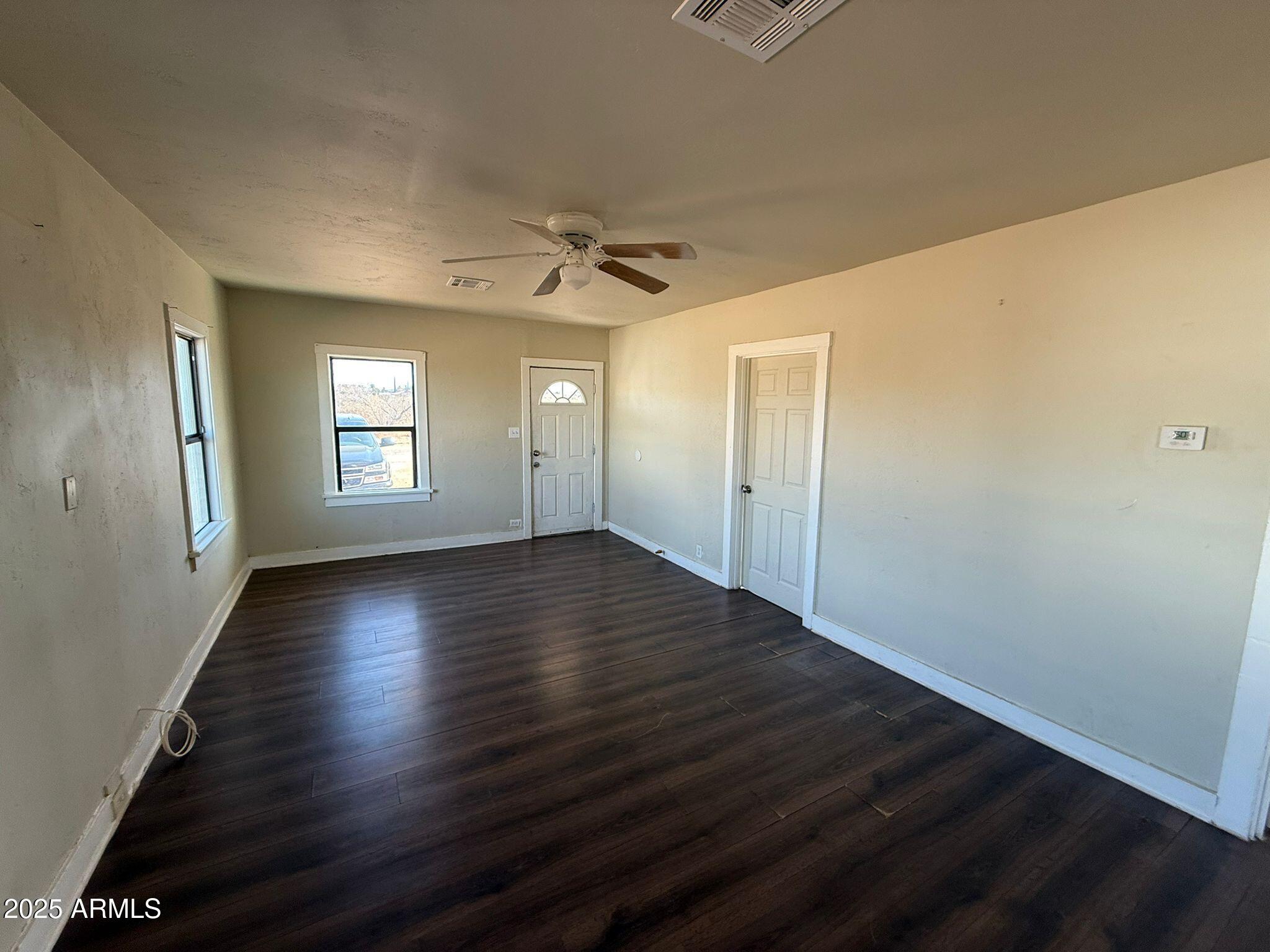 2082 North Cougar Place Douglas, AZ 85607 - Photo 3 of 16 a view of an empty room with wooden floor and a window