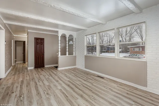 a view of an empty room with a window and wooden floor