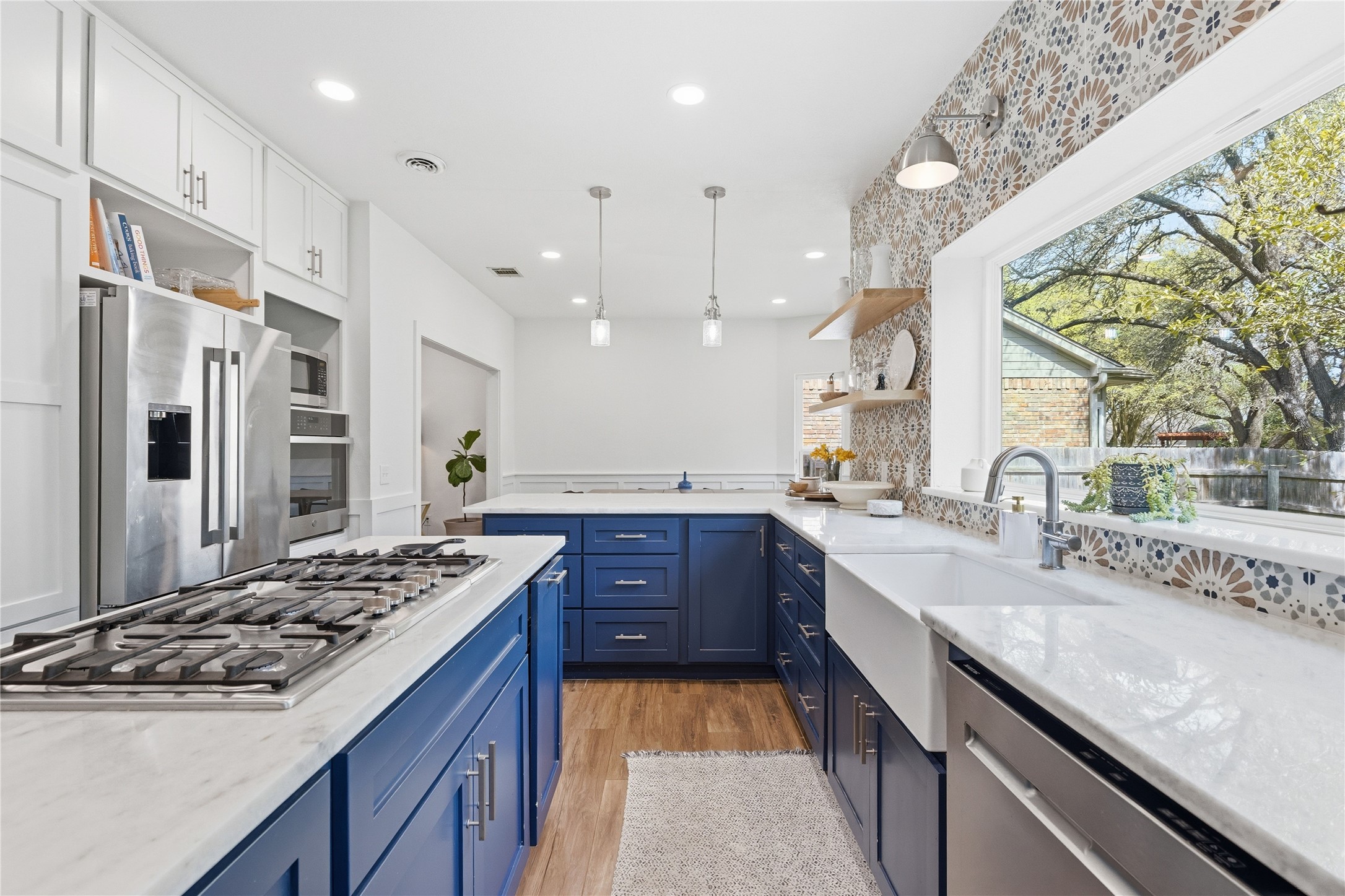 6310 Walebridge Lane Austin, TX 78739 - Photo 13 of 40 Kitchen with open shelves, stainless steel appliances, light stone countertops, and blue cabinetry