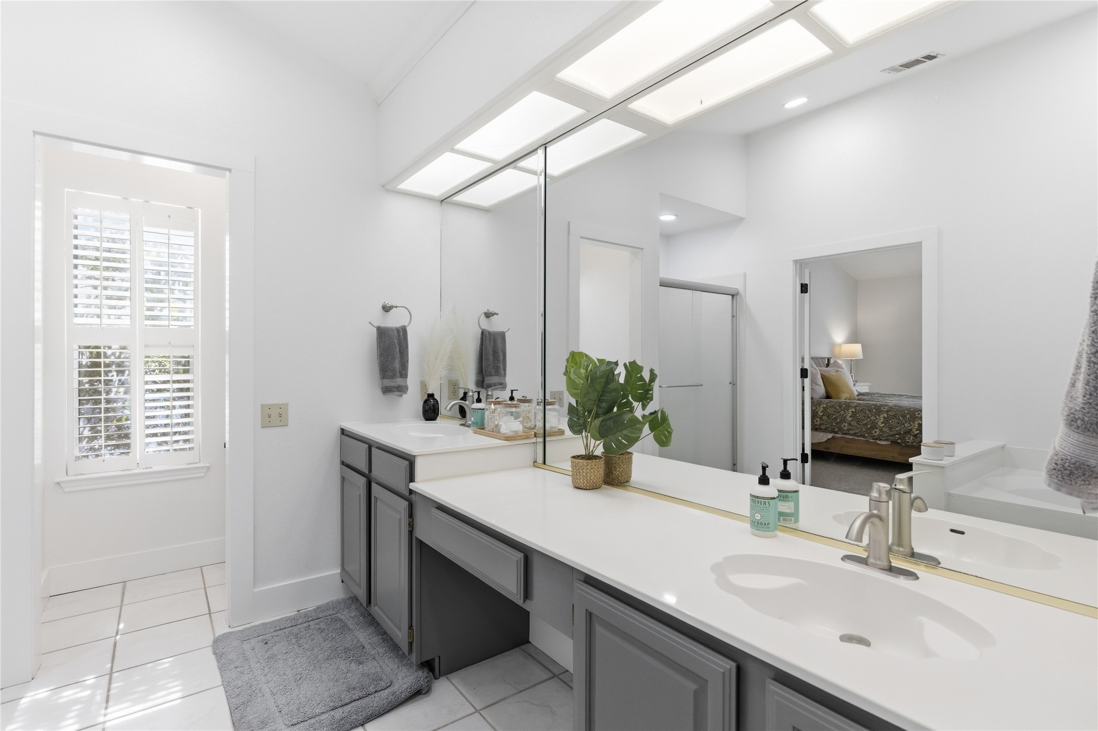 6310 Walebridge Lane Austin, TX 78739 - Photo 27 of 40 Ensuite bathroom featuring double vanity, light tile patterned flooring, and a stall shower