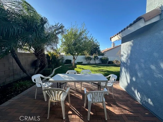 a backyard of a house with table and chairs plants and large trees