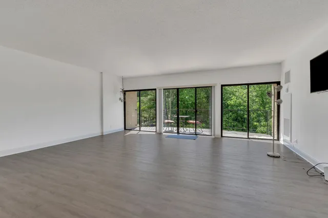 an empty room with wooden floor and windows