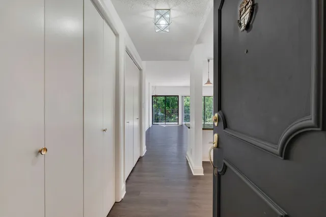 a kitchen with granite countertop a stove a sink a refrigerator and white cabinets with wooden floor