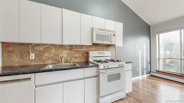 a kitchen with granite countertop white cabinets and white appliances