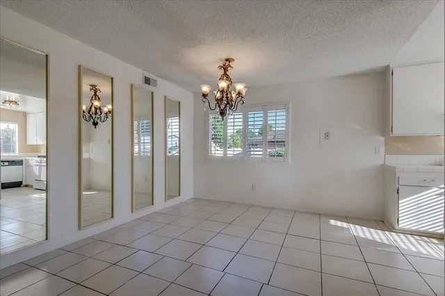 a view of a hallway with bathroom and chandelier