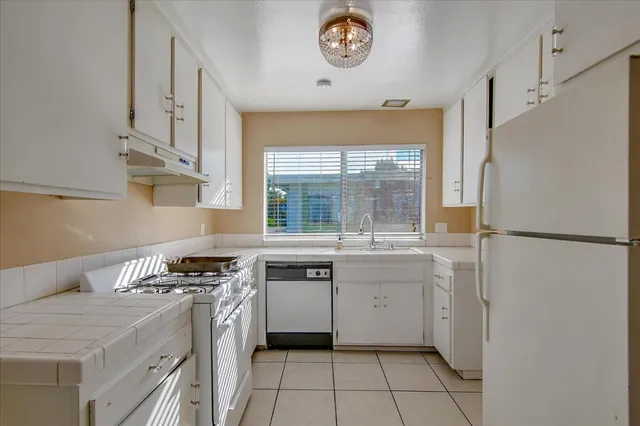 a kitchen with granite countertop white cabinets and white appliances