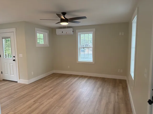 a view of an empty room with wooden floor and a window