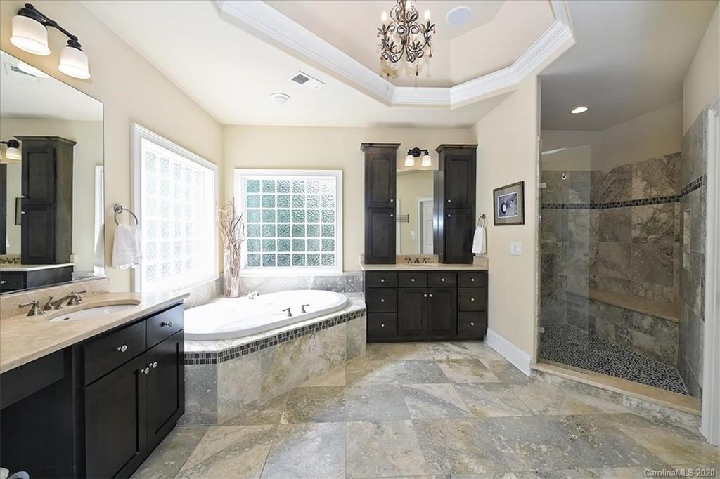 944 Bridlepath Lane Charlotte, NC 28211 - Photo 31 of 48 a spacious bathroom with a double vanity sink a large mirror and a bathtub