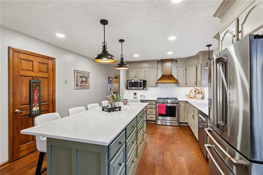 191 Castile Ridge Road Marianna, PA 15345 - Photo 16 of 50 a kitchen with kitchen island a stove a refrigerator and a dining table with wooden floor