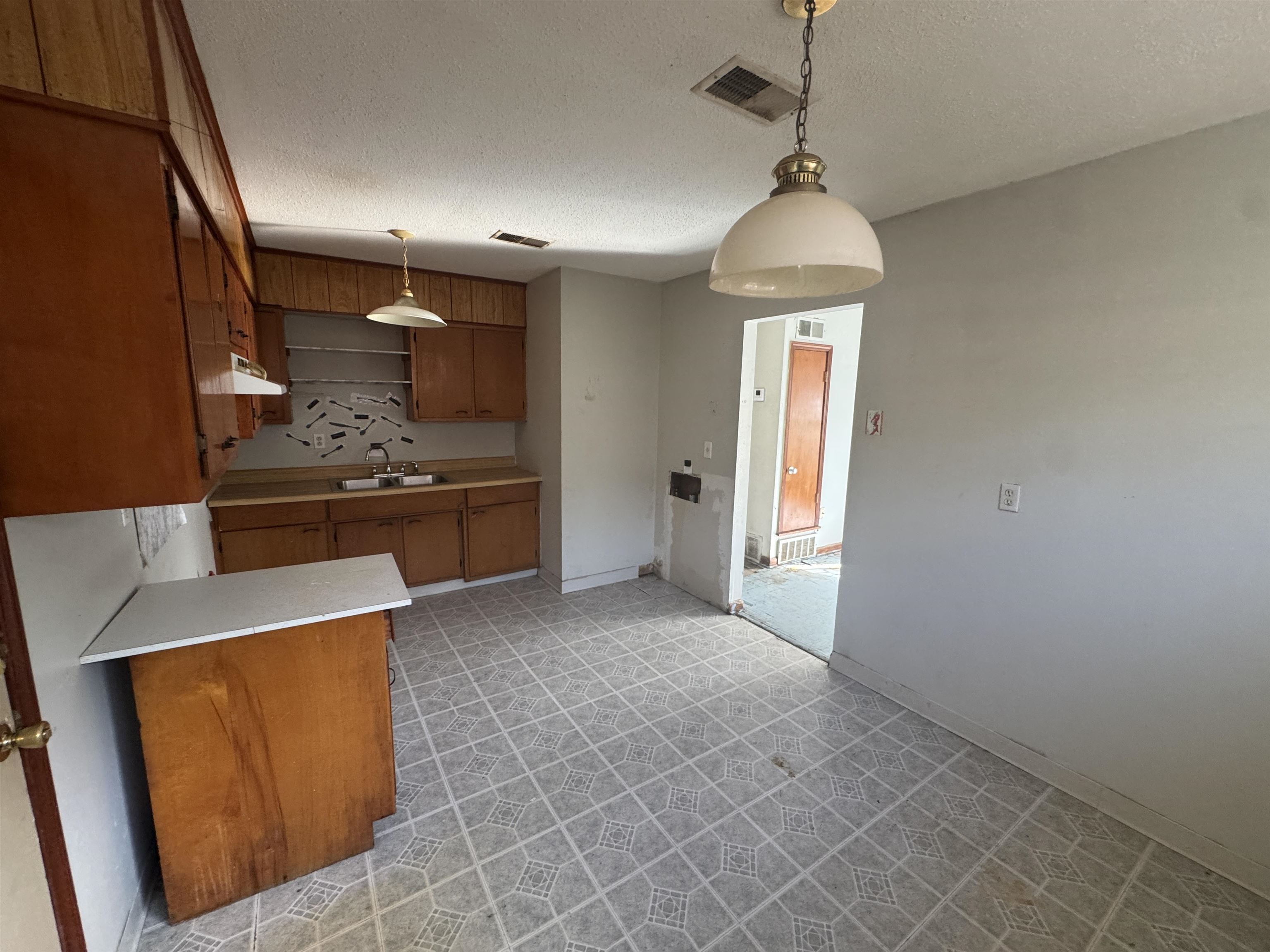 256 Delta Road Memphis, TN 38109 - Photo 14 of 22 Kitchen with brown cabinets, pendant lighting, a textured ceiling, light countertops, and light floors