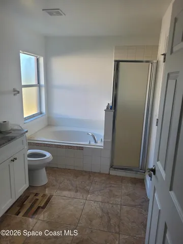a bathroom with a granite countertop toilet sink and mirror