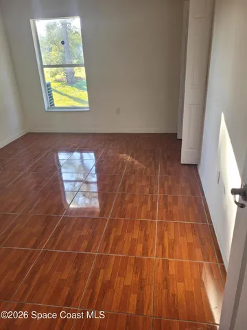 en empty room with window and wooden floor