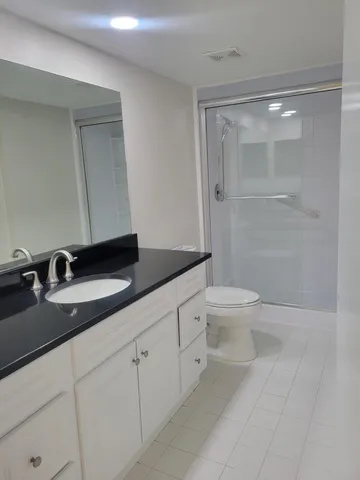 a bathroom with a granite countertop sink a toilet and a mirror