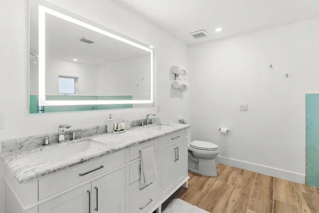 a bathroom with a granite countertop sink toilet a mirror and shower
