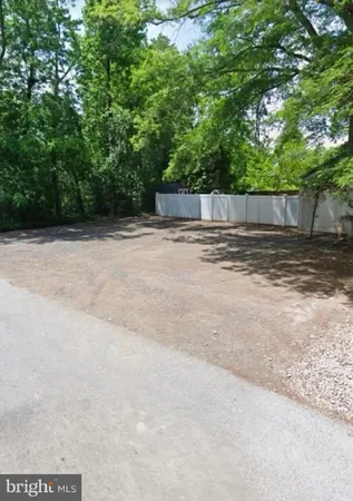 a backyard of a house with large trees and plants