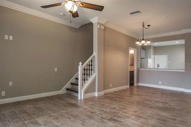 a view of an empty room with wooden floor and staircase