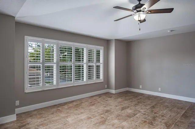 an empty room with a ceiling fan and a window