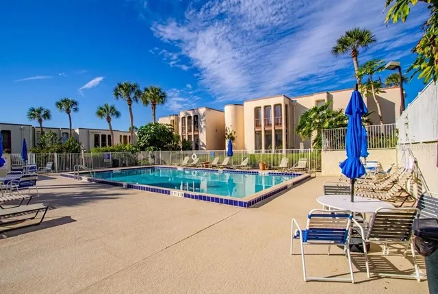 a view of a patio with couches and table and chairs with wooden floor and fence