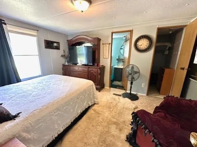 a bedroom with a bed a mirror on dresser and a large window