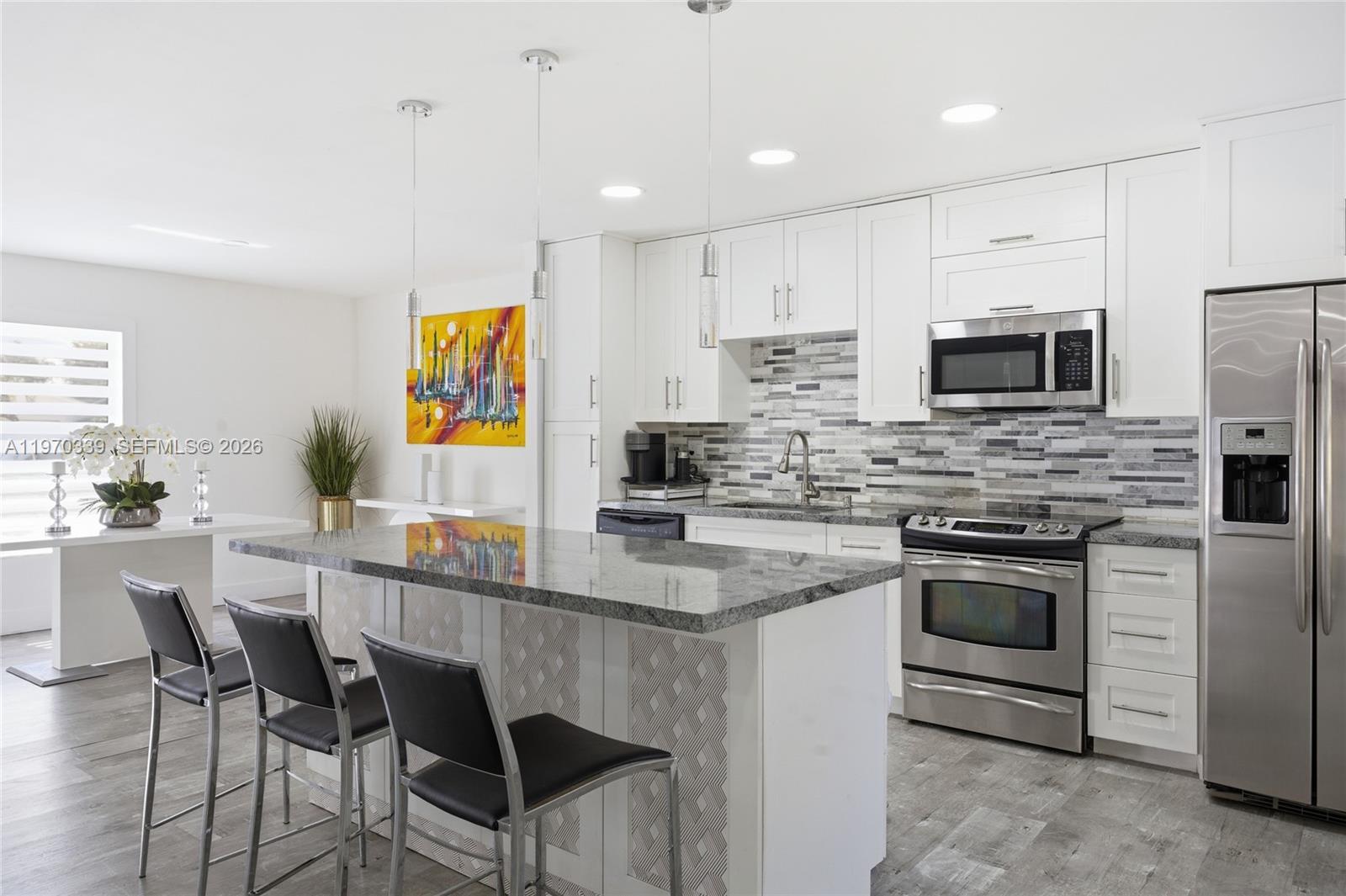 12845 Southwest 72nd Terrace Miami, FL 33183 - Photo 12 of 33 a kitchen with stainless steel appliances granite countertop a stove a sink a microwave a dining table and chairs