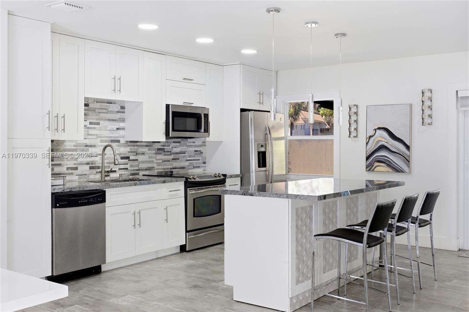 12845 Southwest 72nd Terrace Miami, FL 33183 - Photo 16 of 33 a kitchen with stainless steel appliances kitchen island granite countertop a stove a sink a refrigerator and white cabinets