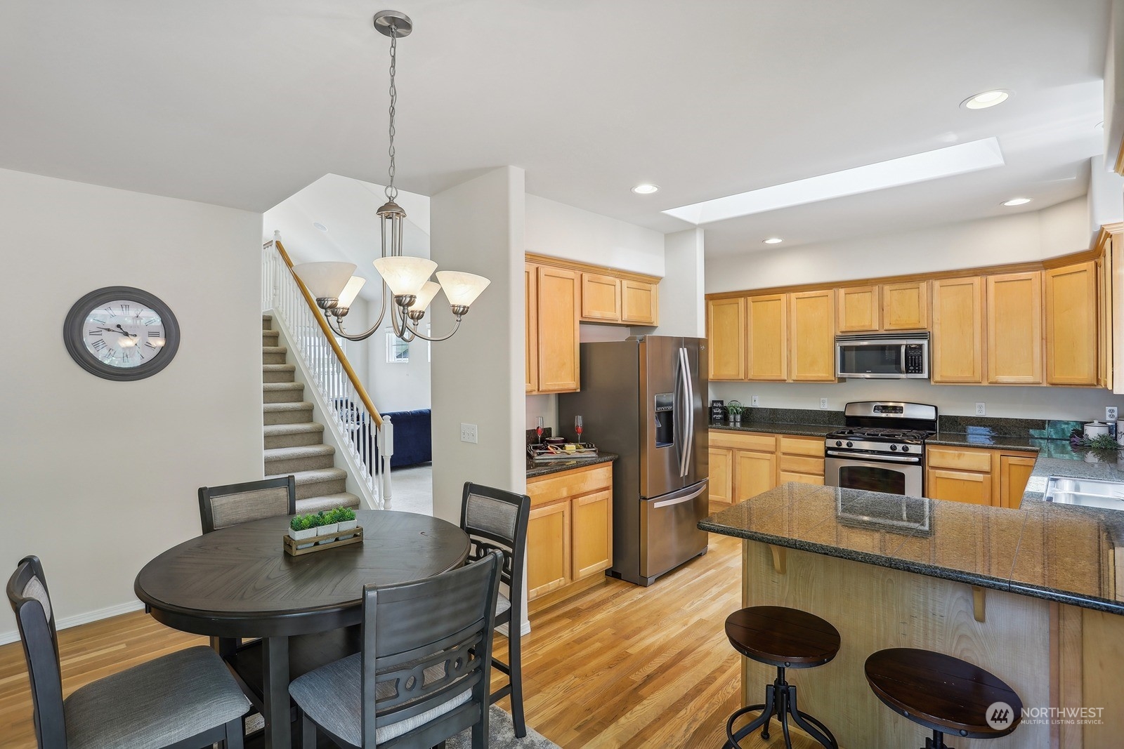 22712 30th Court Southeast Bothell, WA 98021 - Photo 7 of 38 a kitchen with stainless steel appliances granite countertop a stove a refrigerator a dining table and chairs with wooden floor