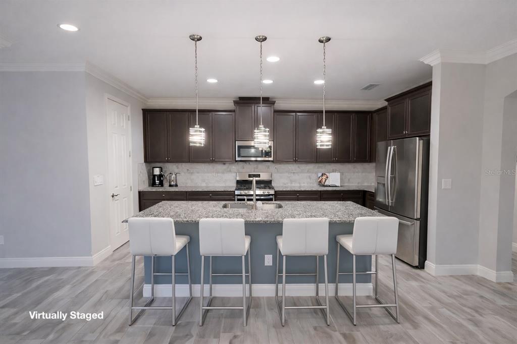 6204 Colmar Place Apollo Beach, FL 33572 - Photo 16 of 57 a kitchen with stainless steel appliances kitchen island granite countertop a dining table chairs and a refrigerator