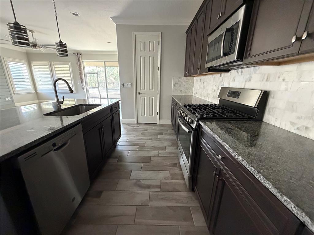 6204 Colmar Place Apollo Beach, FL 33572 - Photo 32 of 57 a kitchen with stainless steel appliances granite countertop a sink stove and microwave