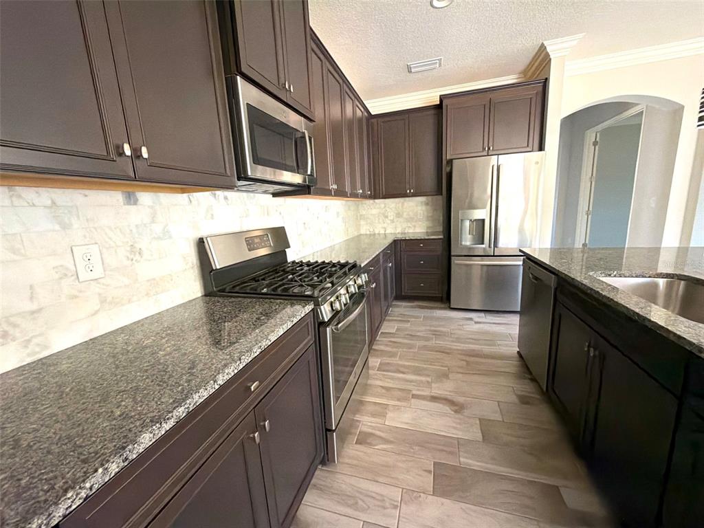 6204 Colmar Place Apollo Beach, FL 33572 - Photo 44 of 57 a kitchen with stainless steel appliances granite countertop a stove a sink and a refrigerator