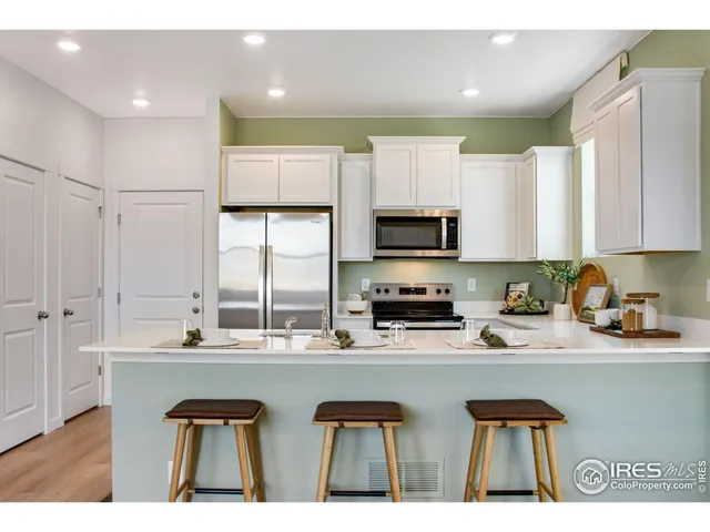 a kitchen with stainless steel appliances a sink a stove a refrigerator cabinets and a window