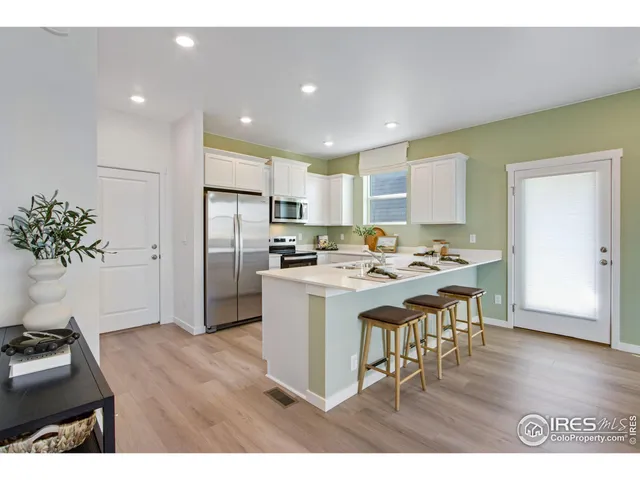 a open kitchen with kitchen island a refrigerator stove a sink dishwasher and a dining table with wooden floor